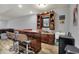 Basement bar featuring bar seating, wooden shelving with sports memorabilia, sink, and mini fridge at 5942 Tioga Ct, Bargersville, IN 46106