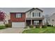 Charming two-story home featuring a red brick facade, attached garage, and manicured front yard at 6420 Greenspire Pl, Indianapolis, IN 46221