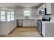 Modern kitchen with stainless steel appliances, white cabinets, and bright natural light from window at 6420 Greenspire Pl, Indianapolis, IN 46221