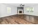 Cozy living room featuring wood flooring, a ceiling fan, a stone fireplace, and natural light at 6837 W Burlington Dr, McCordsville, IN 46055