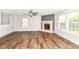 Spacious living room featuring wood flooring, a ceiling fan, a stone fireplace, and natural light at 6837 W Burlington Dr, McCordsville, IN 46055