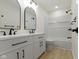 Bright bathroom featuring a double vanity with black hardware, arched mirrors, and a tiled shower/tub combo at 7907 Oakdale Ln, Indianapolis, IN 46214