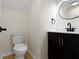 Contemporary half bathroom featuring a round mirror, black fixtures, wood floor, and white walls at 7907 Oakdale Ln, Indianapolis, IN 46214