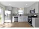 Bright kitchen features stainless steel appliances, white cabinets, gray subway tile backsplash, and wood floor at 7907 Oakdale Ln, Indianapolis, IN 46214