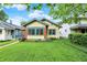 Charming yellow home with green trim, brick accents, a well-manicured lawn and beautiful landscaping at 844 N Emerson Ave, Indianapolis, IN 46219