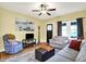 Inviting living room with warm yellow walls, ceiling fan, and cozy seating arrangement at 844 N Emerson Ave, Indianapolis, IN 46219