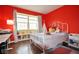 Colorful bedroom features hard wood floors, bright red walls, and light from the window at 9718 Jupiter Pass, Carmel, IN 46032