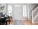 Bright foyer featuring stairs and a piano with natural light from sheer curtained windows at 9718 Jupiter Pass, Carmel, IN 46032