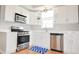 Bright kitchen features modern white cabinetry, stainless steel appliances, and a stylish blue accent rug at 9718 Jupiter Pass, Carmel, IN 46032
