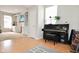 Bright living room showcasing a piano, built-in shelving, and light wood floors at 9718 Jupiter Pass, Carmel, IN 46032