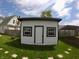 This backyard shed features white siding, a black roof, and is well-lit by windows at 1035 Albany St, Indianapolis, IN 46203