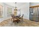Cozy dining area features a round wood table, tile flooring, and modern stainless steel refrigerator at 1105 Wild Ridge Blvd, Brownsburg, IN 46112