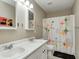 Bathroom featuring double sinks, playful wall art, a colorful shower curtain, and neutral beige walls at 11121 Godfrey Dr, Noblesville, IN 46060