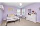 A cheerful bedroom with light purple walls, carpeted floors, large windows, and cozy, patterned bedding at 11121 Godfrey Dr, Noblesville, IN 46060