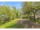 Gravel driveway leading to a backyard with mature trees and green grass at 1215 N Pershing Ave, Indianapolis, IN 46222