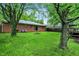 Large backyard with a fire pit, playset, and mature trees, ideal for Gathering fun at 1225 N Graham Ave, Indianapolis, IN 46219