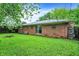 Spacious backyard with a well-maintained lawn and a charming brick house in the background at 1225 N Graham Ave, Indianapolis, IN 46219