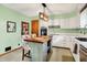 Cozy kitchen featuring white cabinets, stainless steel appliances, an island with seating and a light green accent wall at 1225 N Graham Ave, Indianapolis, IN 46219