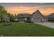 Charming brick home featuring an attached three-car garage, well-manicured lawn, and colorful garden beds at 1297 Morningside Dr, Greenfield, IN 46140