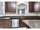 Kitchen with stainless steel dishwasher, dark wood cabinets, and speckled granite countertops at 13499 Molique Blvd, Fishers, IN 46037