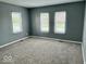 Bright bedroom with neutral gray carpet and three windows filling the room with sunlight at 1715 S Madison St, Muncie, IN 47302