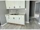 A modern kitchen featuring white cabinets and a stainless steel double sink with gray walls and wood-look vinyl flooring at 1715 S Madison St, Muncie, IN 47302