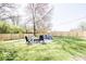 Level, grassy back yard features a fire pit with colorful outdoor seating surrounded by a wooden fence at 2763 Streamside Dr, Columbus, IN 47203