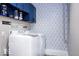 Bright laundry room features new washer/dryer, blue cabinets, and geometric wallpaper at 2763 Streamside Dr, Columbus, IN 47203