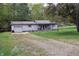 A gray house on a lot with a gravel driveway, offering rustic charm and privacy at 3282 S Conservation Club Rd, Morgantown, IN 46160