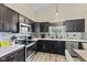 Modern kitchen featuring stainless steel appliances, dark cabinets, light countertops, and stylish backsplash at 3311 Stoddard Pl, Indianapolis, IN 46217