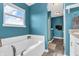 Blue bathroom with natural light, bathtub, and tile floors at 401 Shadetree Ln, Sheridan, IN 46069