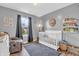Bedroom with grey walls, white crib, recliner, dark curtains and decor at 401 Shadetree Ln, Sheridan, IN 46069