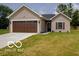 Charming one-story home featuring a well-manicured lawn, a brown garage door, and complementary siding at 403 Fox Ridge Ct, Shelbyville, IN 46176