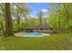 A stone-clad home sits next to an inground pool in a wooded lot with plenty of privacy at 4475 Berkshire Rd, Indianapolis, IN 46226