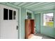 Enclosed porch area with mint green walls, a door to the outside, and bright natural light at 4941 Mathews Ave, Indianapolis, IN 46227