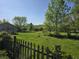 Large grassy backyard, partly fenced, and bordered with mature trees at 5103 W Vermont St, Indianapolis, IN 46224