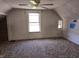 Attic bedroom featuring tan carpet, white walls, and bright light from the window at 5103 W Vermont St, Indianapolis, IN 46224