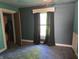 Bedroom with blue walls, carpet floors and bright light from the window with dark curtains at 5103 W Vermont St, Indianapolis, IN 46224