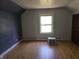 Attic bedroom featuring wood floors, gray accent wall, and bright light from the window at 5103 W Vermont St, Indianapolis, IN 46224