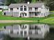 Beautiful home overlooking lake featuring well-manicured lawn, large windows, and tranquil waters reflecting the home's facade at 515 E Hoover Dr, Nineveh, IN 46164