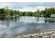 Scenic lakefront view showcases calm waters reflecting the cloudy sky, framed by verdant trees along the distant shoreline at 515 E Hoover Dr, Nineveh, IN 46164
