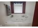 Close-up of a bathtub with a window, white tile surround, and a window with valance at 6270 Lancaster Pl, Zionsville, IN 46077