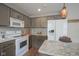 Well-lit kitchen with white appliances, gray cabinets, granite countertops, and wood floor at 6270 Lancaster Pl, Zionsville, IN 46077