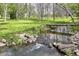 Picturesque backyard creek featuring a bridge amidst lush greenery and mature trees at 6340 W 800 S, Pendleton, IN 46064