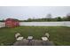 Spacious backyard with lush green grass, a red storage shed, and a white privacy fence at 7814 Crooked Meadows Dr, Indianapolis, IN 46268