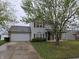 Charming two-story home featuring vinyl siding, brick accents, an attached two-car garage and mature trees in the front yard at 7814 Crooked Meadows Dr, Indianapolis, IN 46268