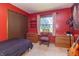 Red bedroom with window, wooden furnishings, and carpet flooring showcases a cozy, personalized space at 8292 E 100 S, Greenfield, IN 46140