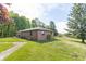Quaint one-story brick home featuring a well-maintained lawn, mature trees, and a charming outdoor deck area at 8292 E 100 S, Greenfield, IN 46140