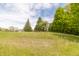 Scenic view of a home nestled among mature trees in a large, open field under a partly cloudy sky at 8292 E 100 S, Greenfield, IN 46140