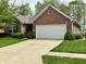 Charming brick home featuring a well-manicured lawn and a spacious two-car garage at 9653 Woodsong Way, Indianapolis, IN 46229
